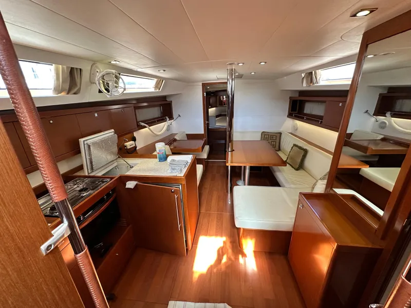 Slide: The Image of Interior of 2012 Beneteau Oceanis 41 yacht, featuring kitchen and dining area with wood finish. - 29