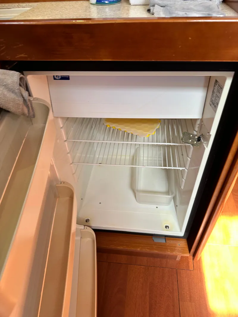 Slide: The Image of Open refrigerator inside 2012 Beneteau Oceanis 41 yacht, showing empty shelves and wooden flooring. - 41