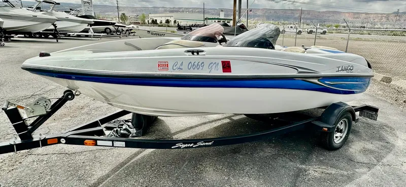 Slide: The Image of 2007 Tango Super Sport boat on trailer, white with blue accents, parked outdoors. - 1