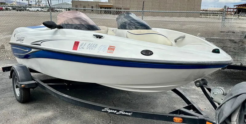 Slide: The Image of 2007 Tango Super Sport boat on trailer, white with blue accents, parked outdoors. - 5