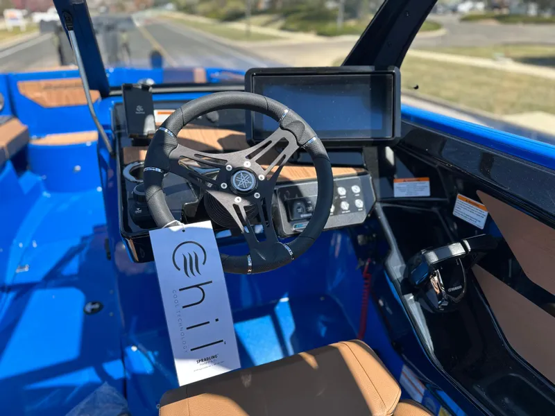 Slide: The Image of 2025 Yamaha Boats 222XE interior with steering wheel and dashboard, featuring blue and brown accents. - 13