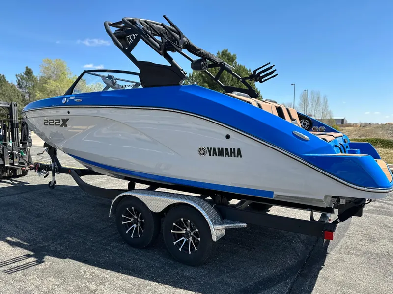 Slide: The Image of 2025 Yamaha Boats 222XE on trailer, blue and white design, parked outdoors. - 2