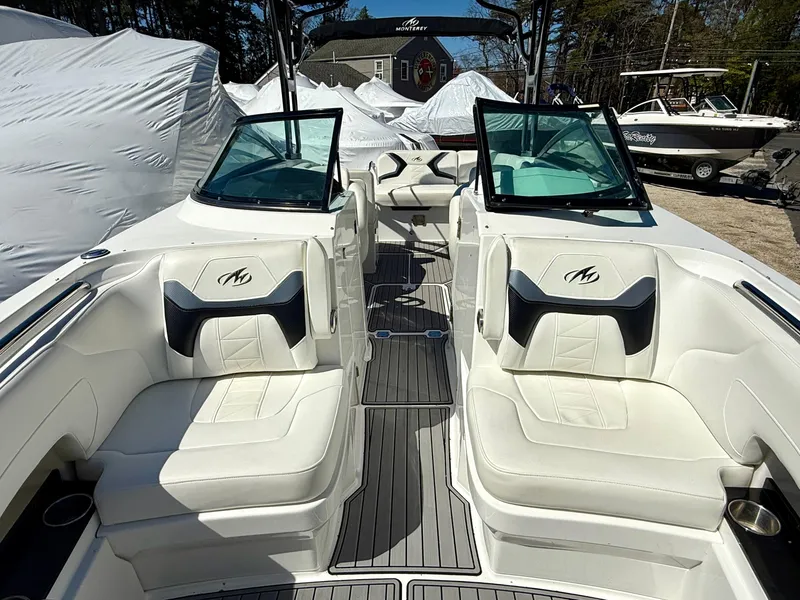 Slide: The Image of 2014 Monterey M5 Sport Boat with white seating and dual windshields, parked outdoors. - 7