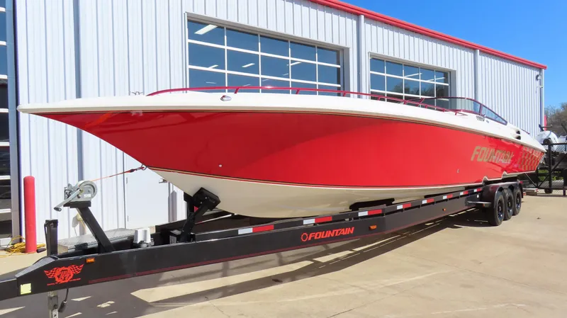 Slide: The Image of Red 2002 Fountain 47 Lightning boat on trailer, parked outside a building. - 2