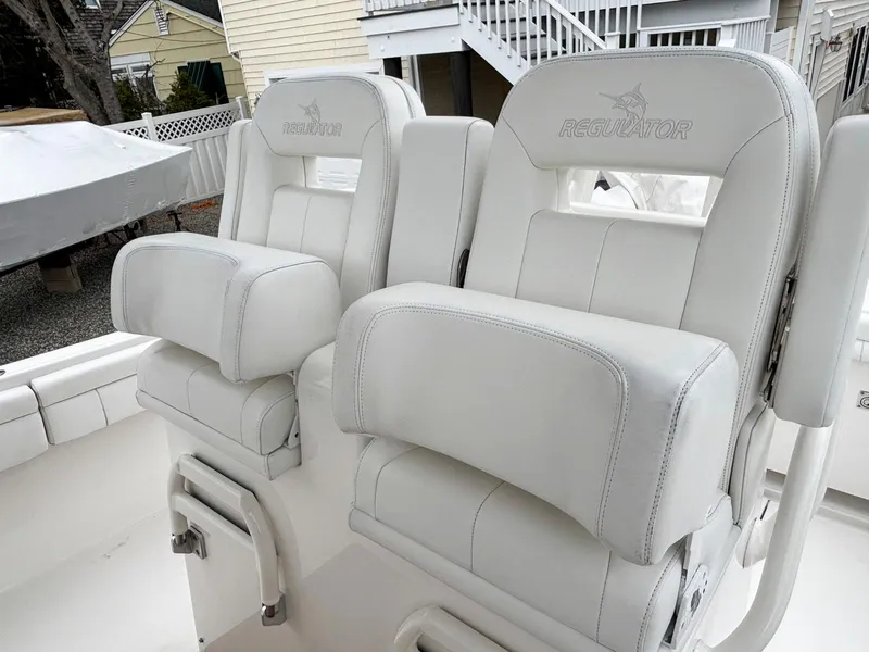 Slide: The Image of 2018 Regulator 28 boat seats, white leather, dual helm chairs, outdoor setting. - 10