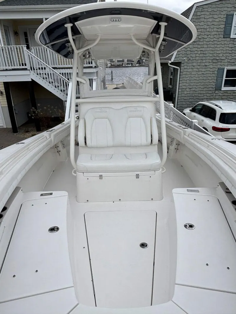 Slide: The Image of 2018 Regulator 28 boat with dual seating and T-top, docked near coastal homes. - 15