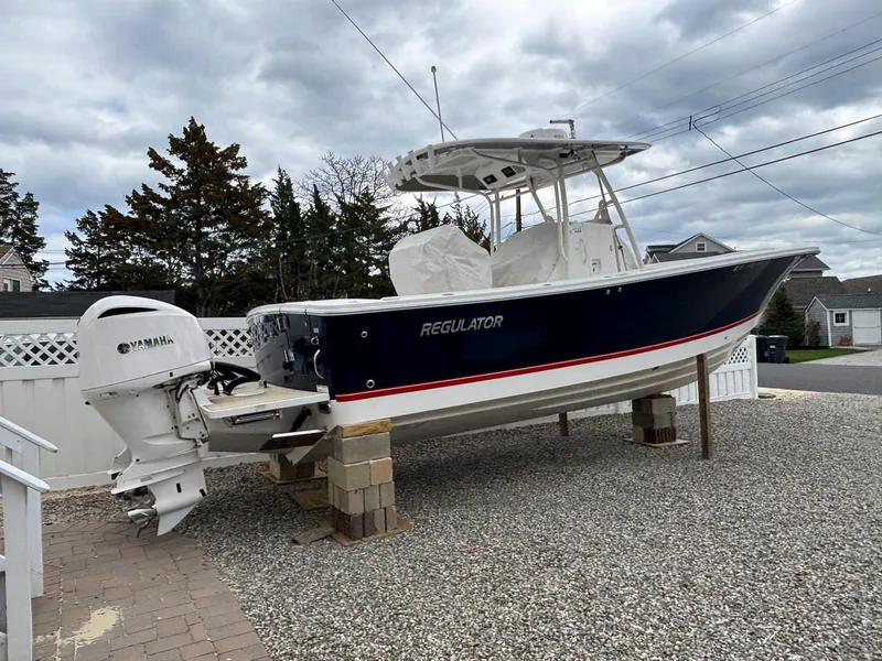 Slide: The Image of 2018 Regulator 28 boat with Yamaha engine on dry dock, gravel surface, cloudy sky. - 2