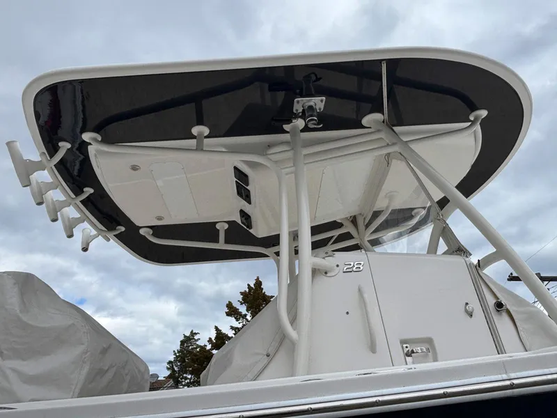 Slide: The Image of 2018 Regulator 28 boat with T-top and rod holders, viewed from below against cloudy sky. - 20