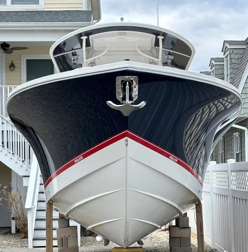 Slide: The Image of 2018 Regulator 28 boat with sleek design, docked near coastal homes. - 3