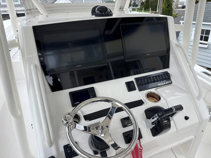 Slide: The Image of 2018 Regulator 28 boat dashboard with dual screens and steering wheel. - 7