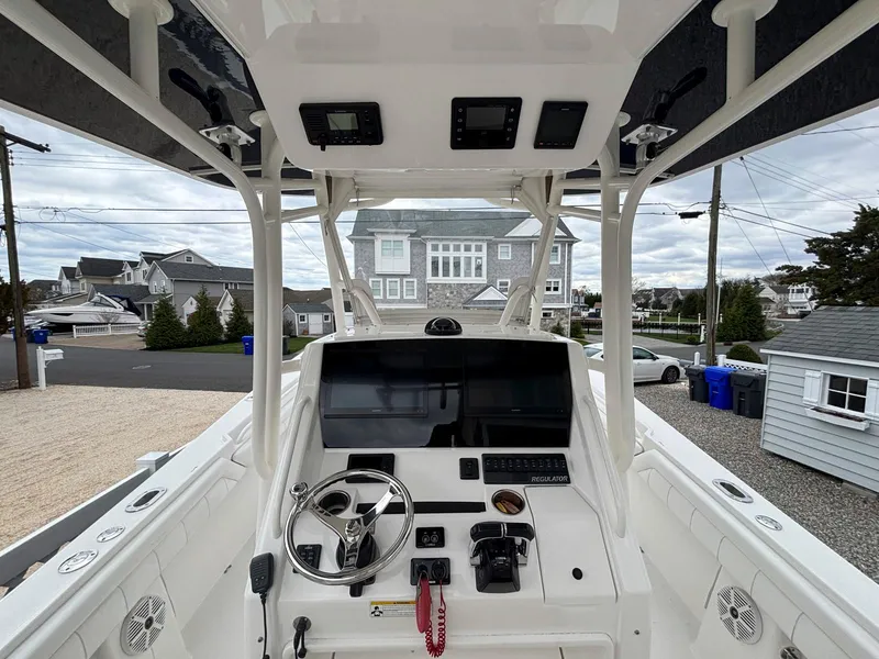 Slide: The Image of 2018 Regulator 28 boat console with steering wheel and navigation equipment, docked in a residential area. - 9