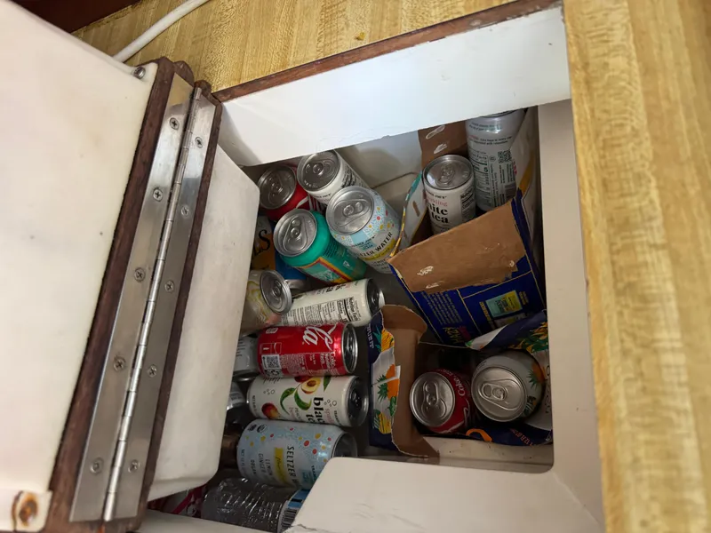 Slide: The Image of Storage compartment in a 1985 Catalina 30 boat filled with assorted beverage cans. - 13
