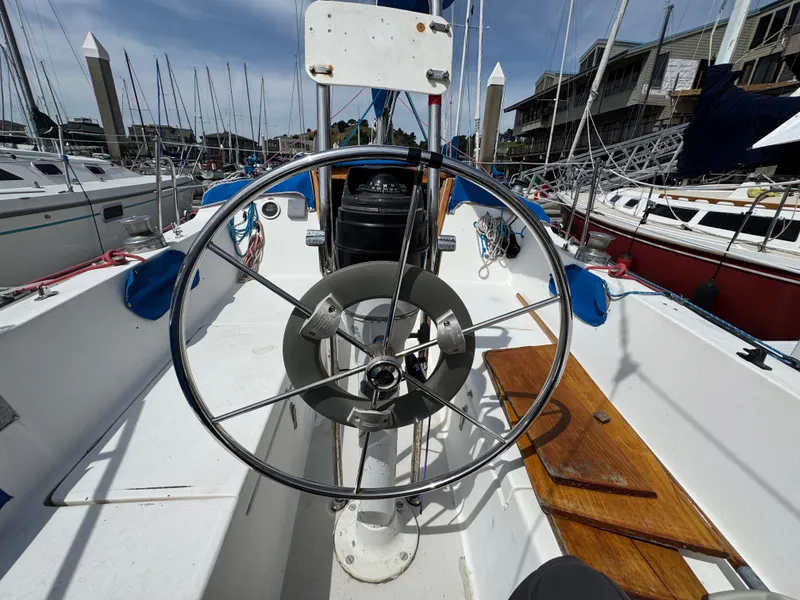 Slide: The Image of Cockpit of a 1985 Catalina 30 sailboat with steering wheel and marina view. - 15