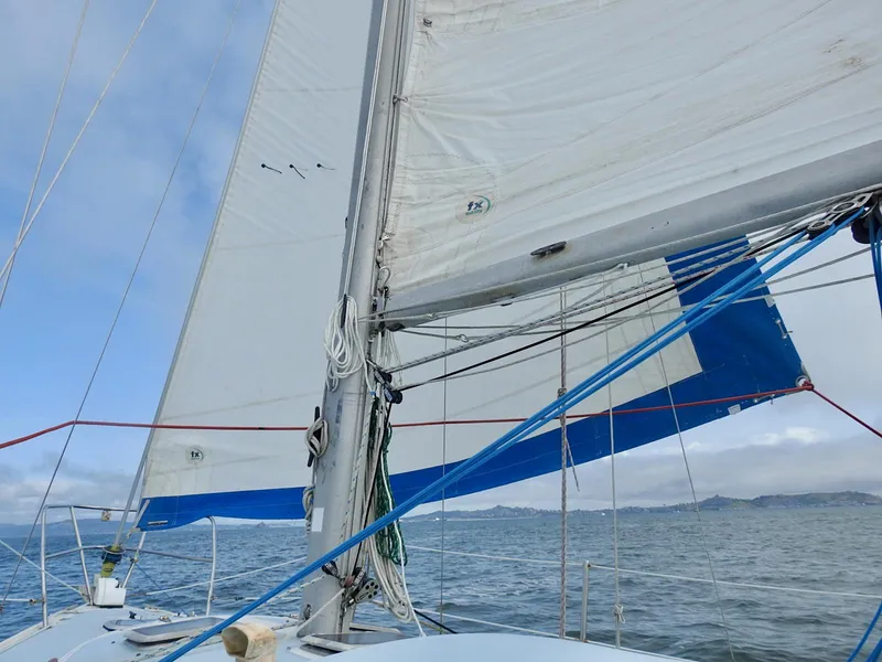 Slide: The Image of 1985 Catalina 30 sailboat on open water, sails unfurled, clear sky. - 32
