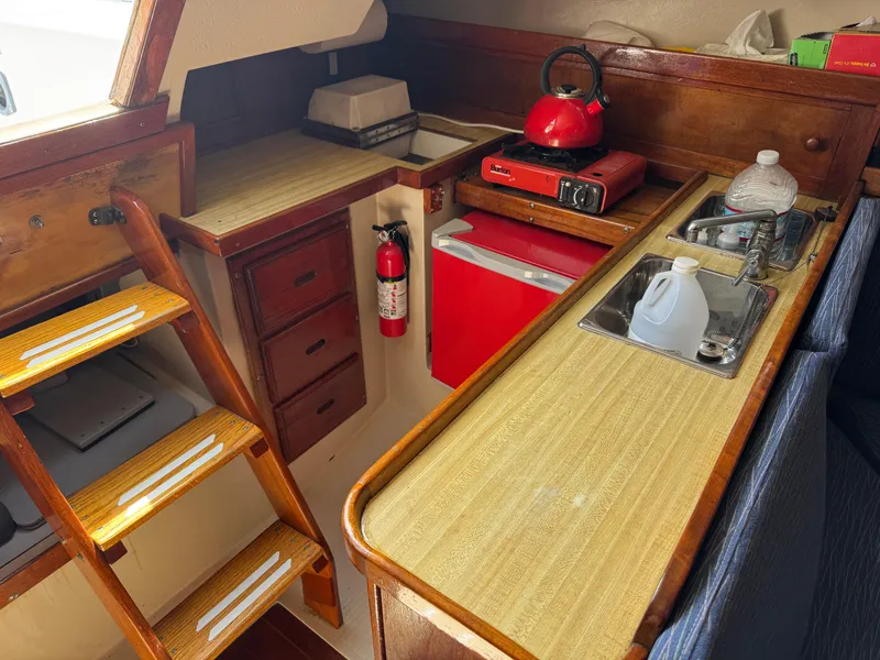 Slide: The Image of 1985 Catalina 30 yacht interior with kitchenette, red kettle, and wooden cabinetry. - 5