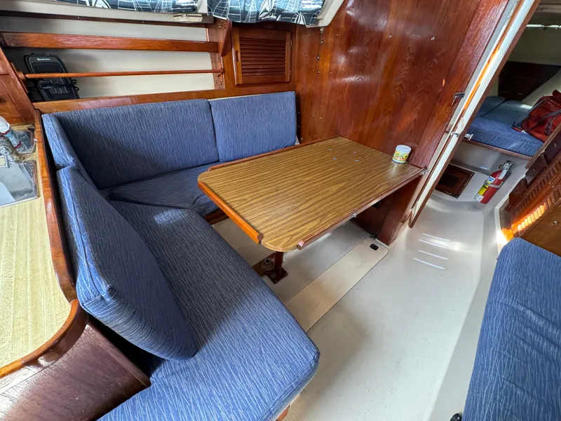 Slide: The Image of Interior of 1985 Catalina 30 sailboat with blue cushioned seating and wooden table. - 7