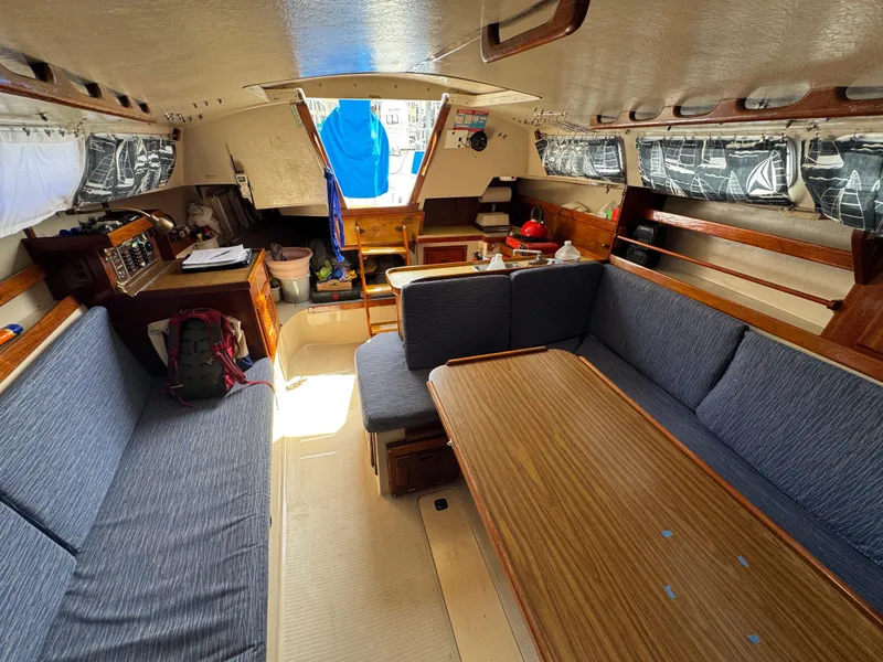 Slide: The Image of Interior of a 1985 Catalina 30 sailboat with blue seating and wooden table. - 8