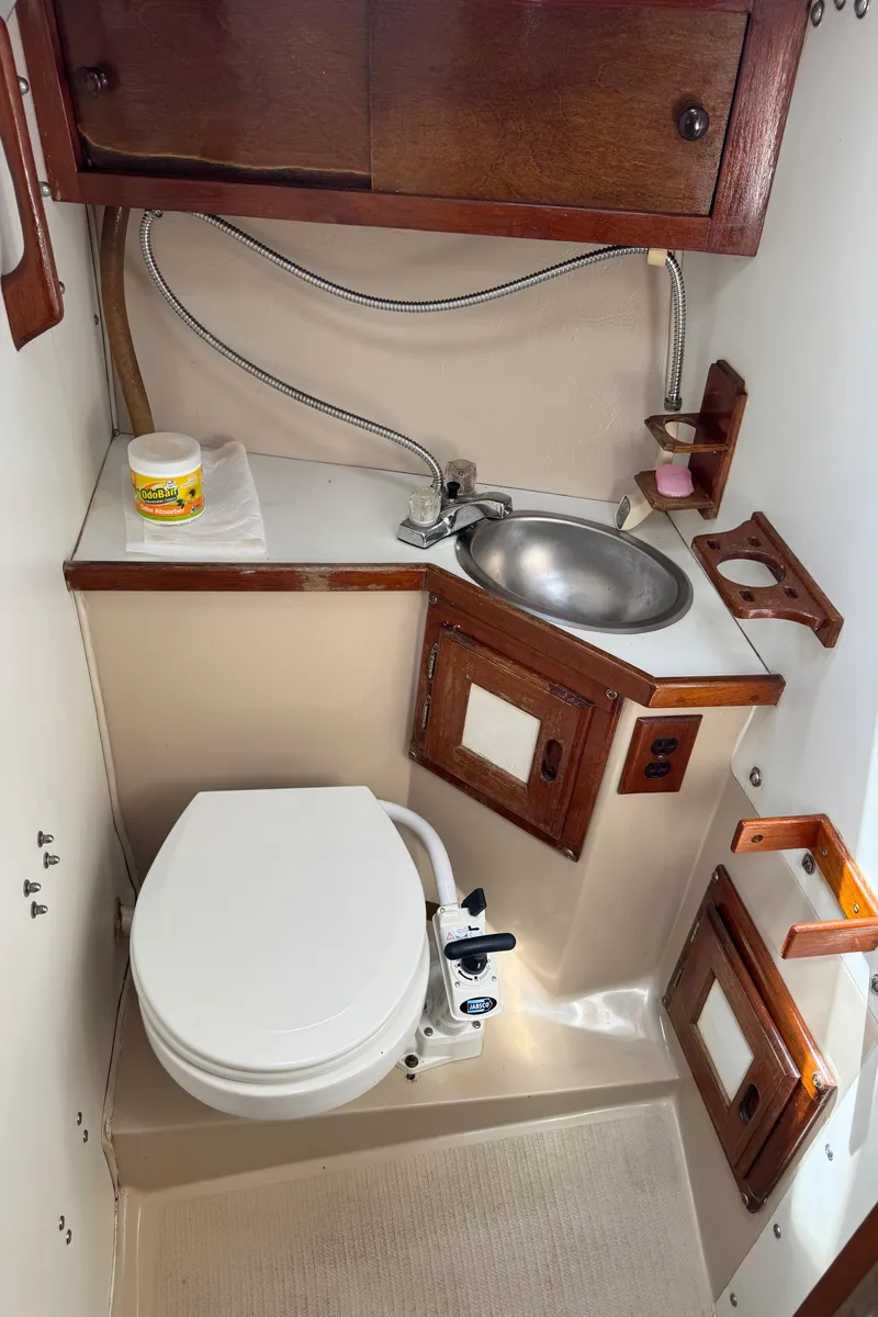 Slide: The Image of 1985 Catalina 30 boat bathroom with sink, toilet, and wooden cabinetry. - 9