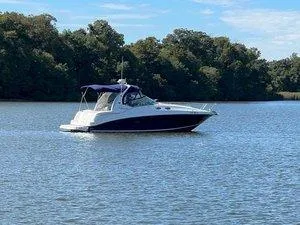 Slide: The Image of 2005 Sea Ray 320 Sundancer boat cruising on a calm lake with trees in the background. - 2