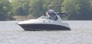 Slide: The Image of 2005 Sea Ray 320 Sundancer cruising on a calm lake with lush green trees in the background. - 4