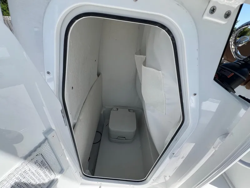Slide: The Image of 2025 Sea Hunt BX22BR boat interior storage compartment with portable toilet. - 14