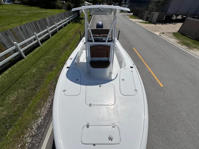 Slide: The Image of 2025 Sea Hunt BX22BR boat on road, top view, white hull, parked near fence. - 17