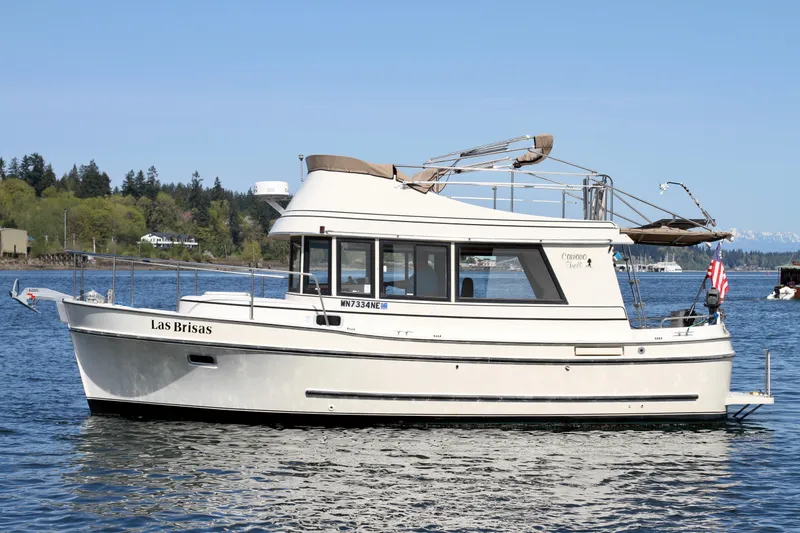 Slide: The Image of 1995 Camano Troll boat on calm water, side view, with trees in the background. - 0
