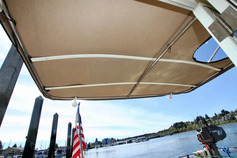 Slide: The Image of 1995 Camano Troll boat canopy with American flag, docked by a scenic waterfront. - 16