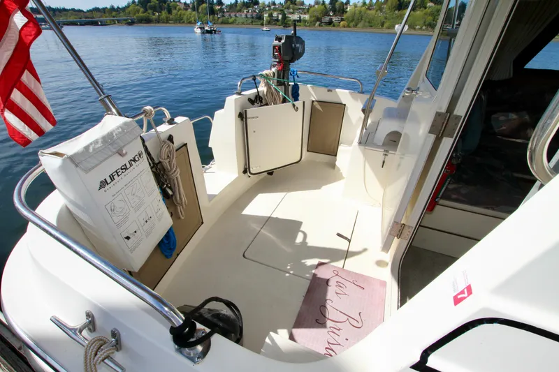 Slide: The Image of 1995 Camano Troll boat deck with safety equipment, docked on a serene lake. - 19