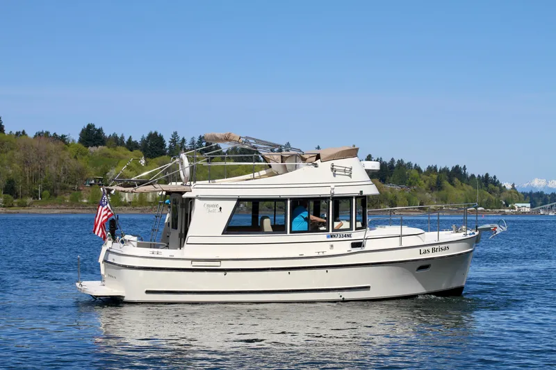 Slide: The Image of 1995 Camano Troll boat cruising on a serene lake with lush green shoreline. - 2