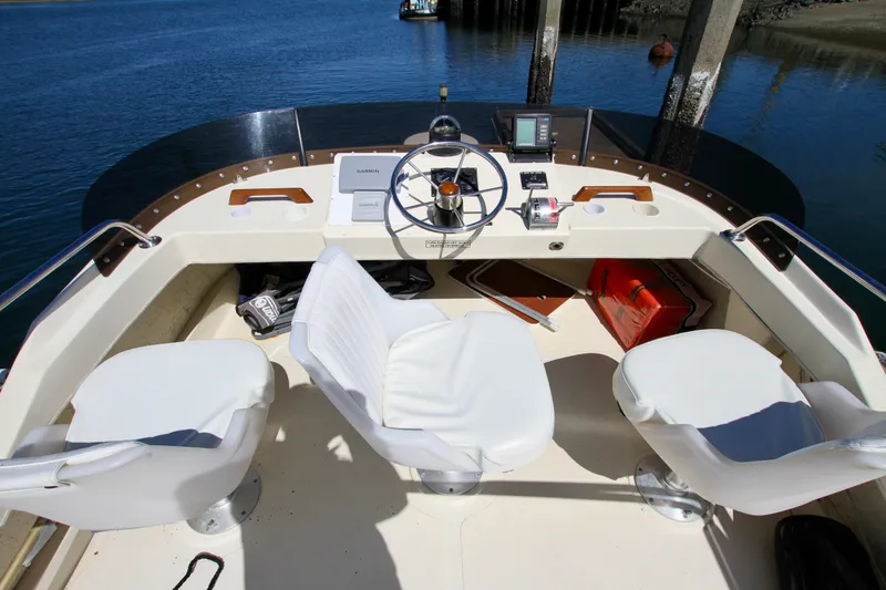 Slide: The Image of 1995 Camano Troll boat cockpit with steering wheel and white seats, docked by the water. - 20