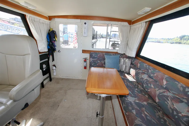 Slide: The Image of Interior of a 1995 Camano Troll boat with seating and table, featuring large windows. - 27