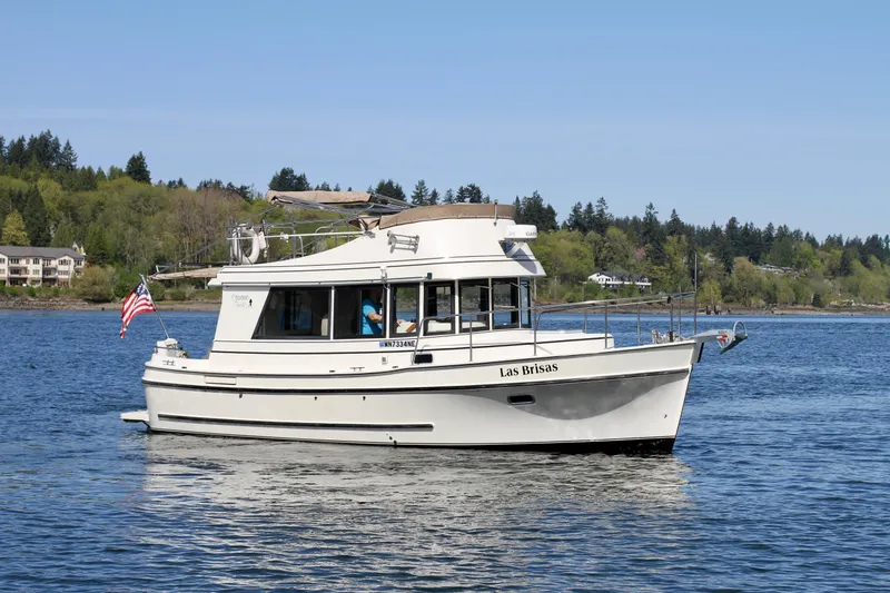 Slide: The Image of 1995 Camano Troll boat cruising on a serene lake with forested shoreline. - 3