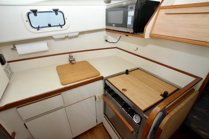 Slide: The Image of Compact kitchen in a 1995 Camano Troll boat with stove, microwave, and wooden countertops. - 31