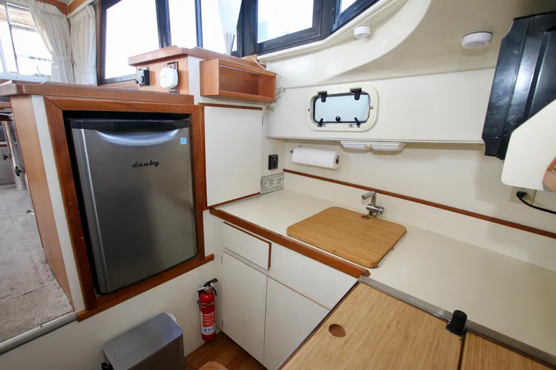 Slide: The Image of 1995 Camano Troll boat kitchen with compact fridge, sink, and wooden countertops. - 32