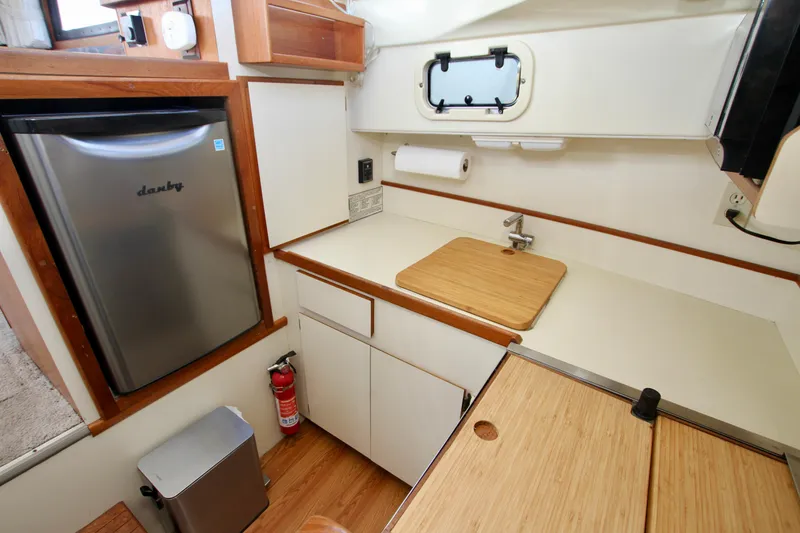 Slide: The Image of Compact kitchen in a 1995 Camano Troll boat with fridge, sink, and wooden countertops. - 33