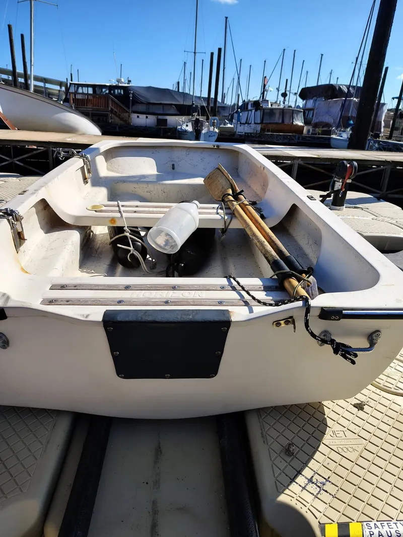 Slide: The Image of 1995 Camano Troll boat docked, featuring oars and equipment, in a sunny marina setting. - 47