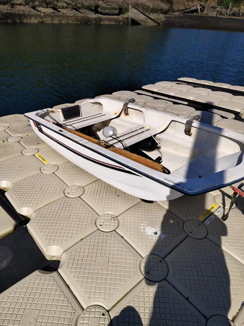 Slide: The Image of 1995 Camano Troll boat docked on a floating platform by the water. - 49