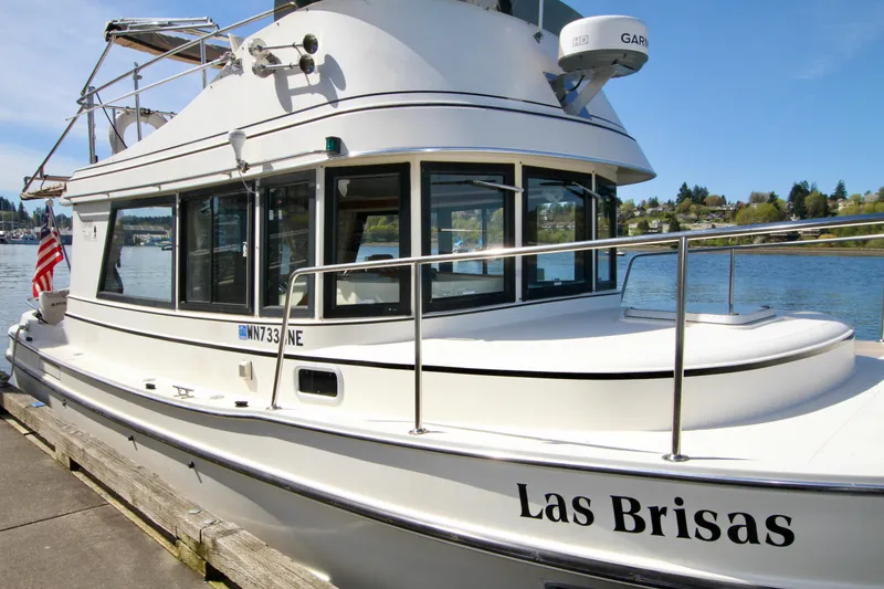 Slide: The Image of 1995 Camano Troll boat "Las Brisas" docked by the water, featuring sleek design and American flag. - 7