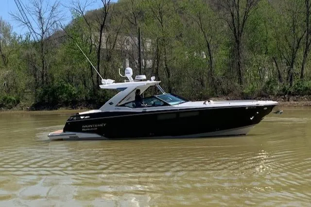 Slide: The Image of 2017 Monterey 378 SE boat cruising on a calm river with lush green trees. - 2