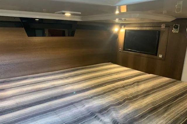 Slide: The Image of Interior cabin of 2017 Monterey 378 SE boat with striped bedding and ambient lighting. - 38