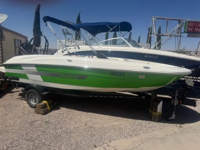 Slide: The Image of 2003 Bayliner Element E18 boat with green and white design on a trailer. - 1