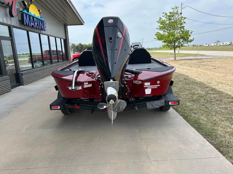 Slide: The Image of 2025 Tracker Savage 215 boat, red, parked outside a marine store. - 3