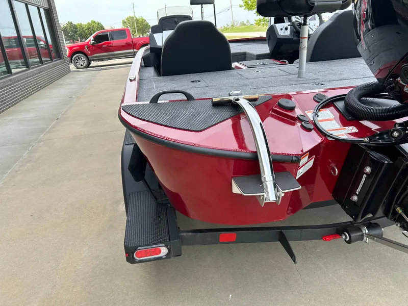 Slide: The Image of 2025 Tracker Savage 215 boat, red exterior, parked on a trailer near a building. - 8