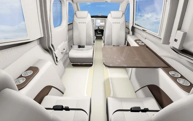 Slide: The Image of Interior of Aron M 80, 2025 model, featuring sleek white seating and a wooden table. - 25