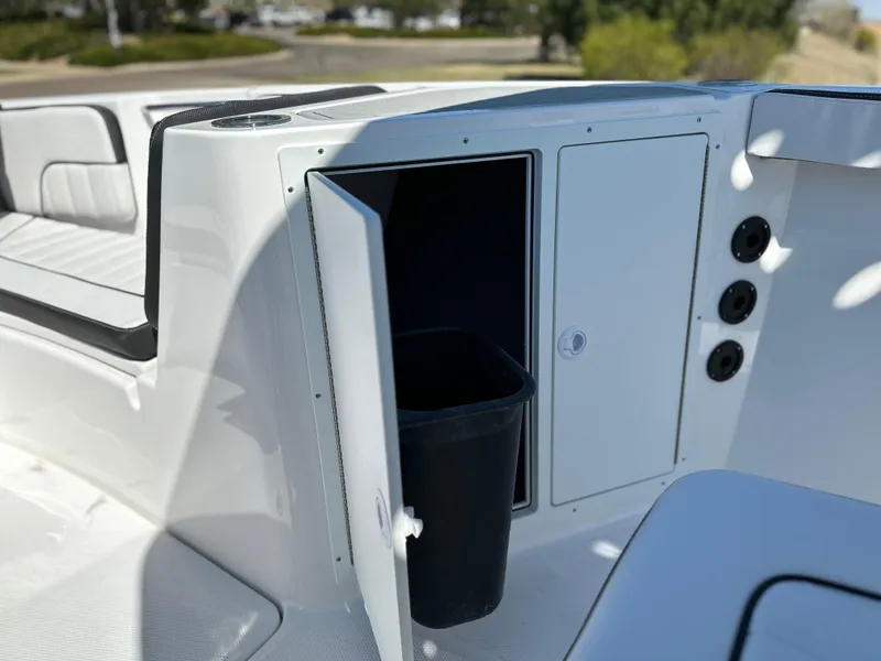 Slide: The Image of 2025 Yamaha Boats 222 FSH Sport storage compartment with open door and trash bin. - 14