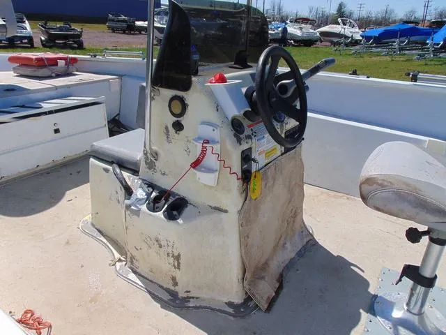 Slide: The Image of 2007 Alumacraft 2072CS boat console with steering wheel and controls, in a marina setting. - 8