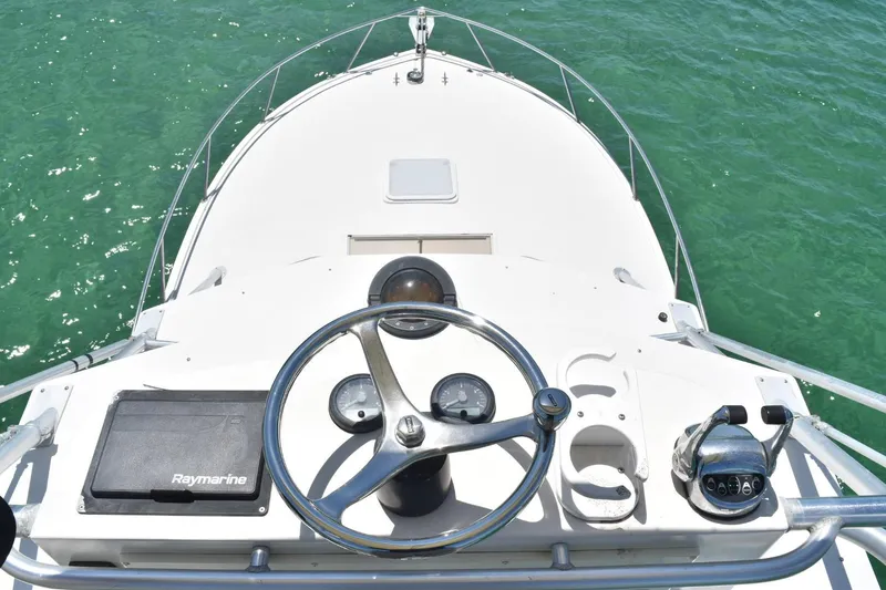 Slide: The Image of 2006 Carolina Classic 32 boat helm with steering wheel and navigation equipment on clear water. - 13