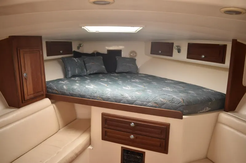 Slide: The Image of Interior cabin of a 2006 Carolina Classic 32 boat with a cozy bed and wooden cabinets. - 14