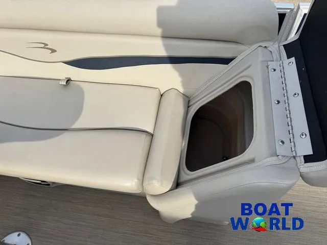 Slide: The Image of 2017 Bennington 21SSX Pontoon seat storage compartment, beige upholstery, Boat World logo. - 21